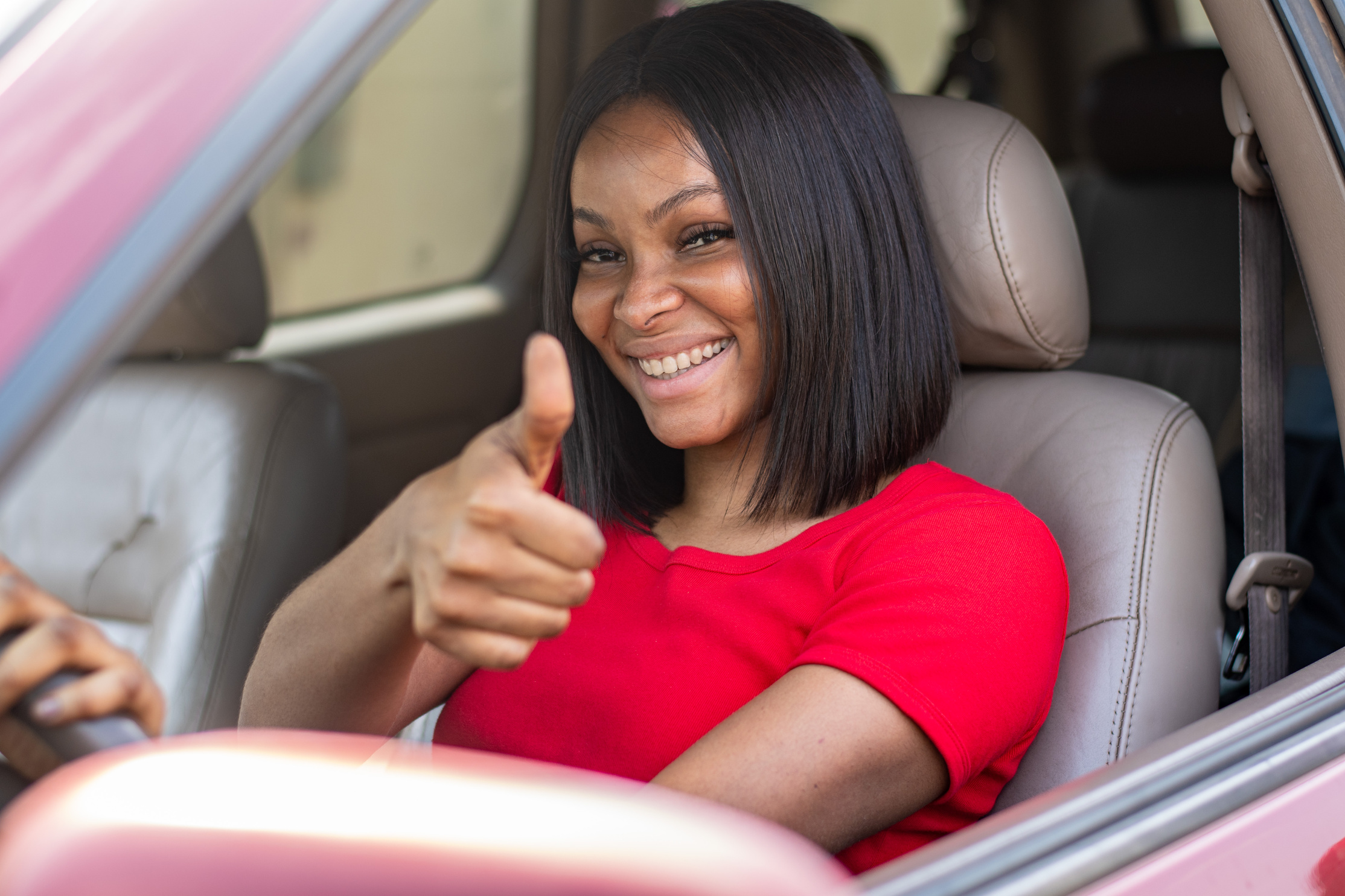 pretty african woman driving her car, does thumbs up