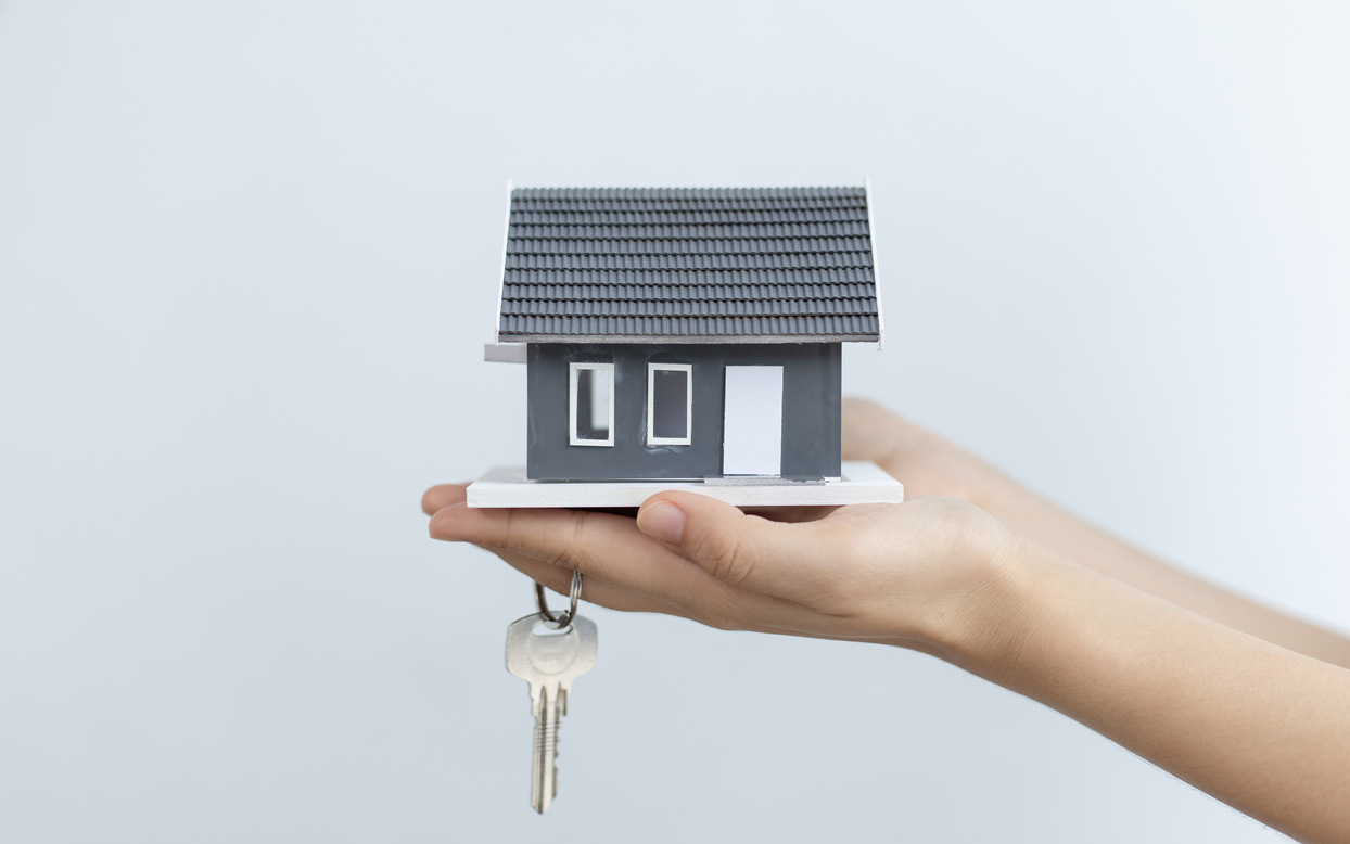 Hand Holding a Miniature House and Key        